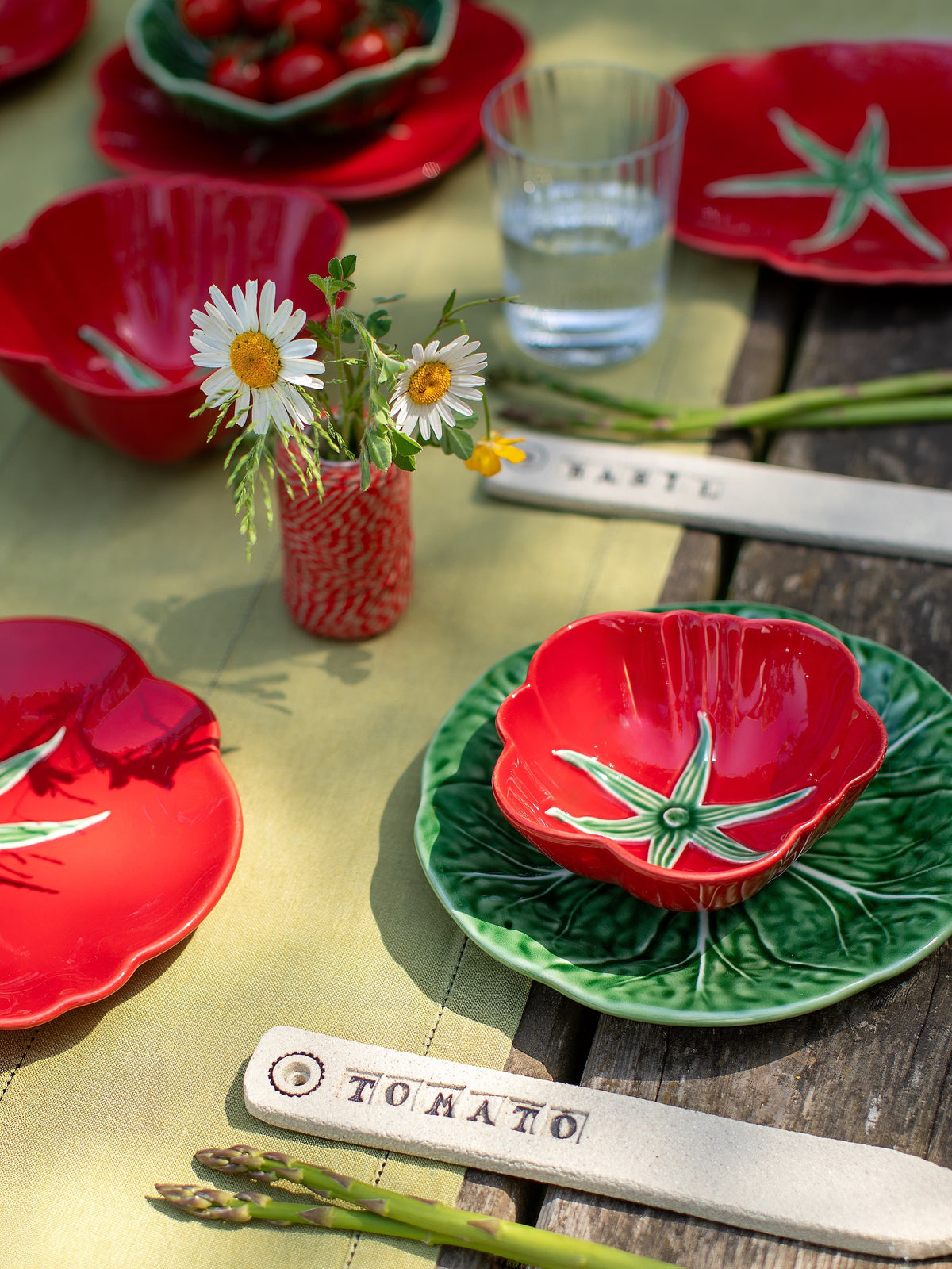 Decorative ceramic plates with tomato designs on a wooden table.