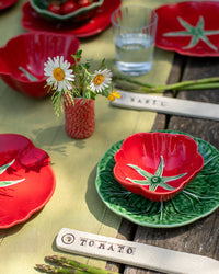 Decorative ceramic plates with tomato designs on a wooden table.