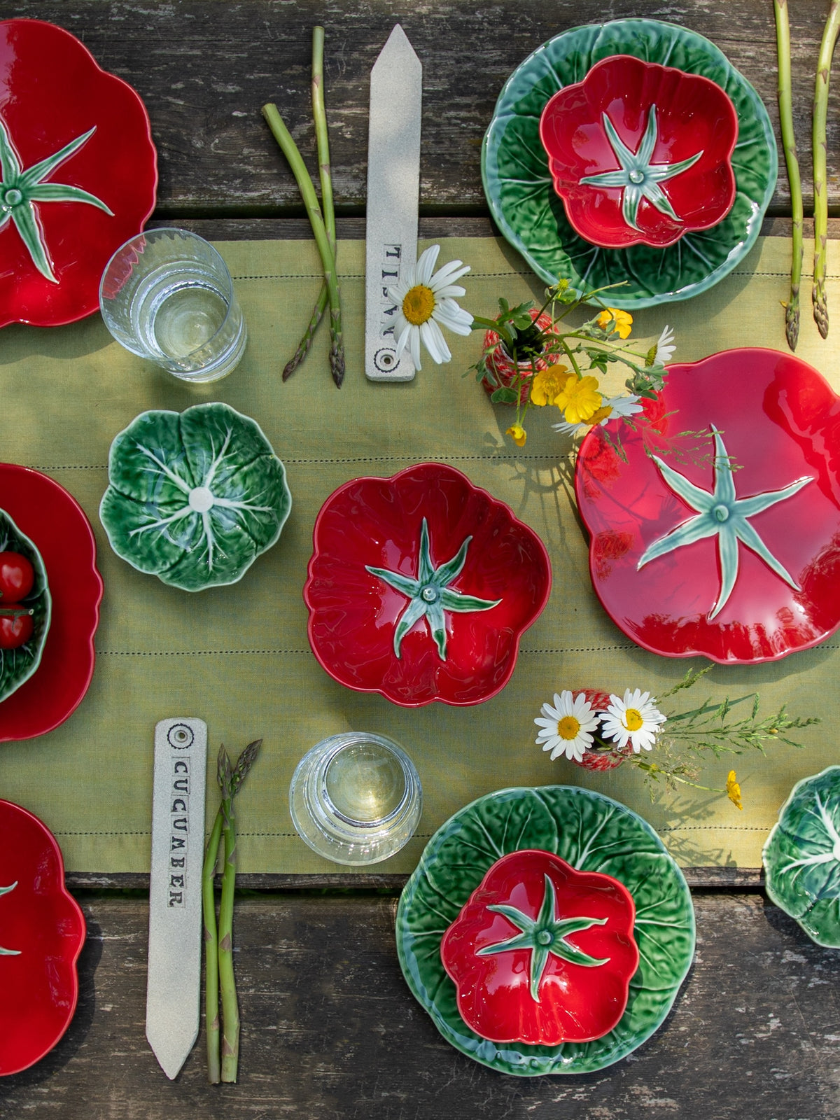 Colourful ceramic plates with tomato and cabbage leaf designs on a wooden table.