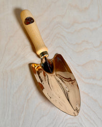 Bronze trowel on a birch ply background