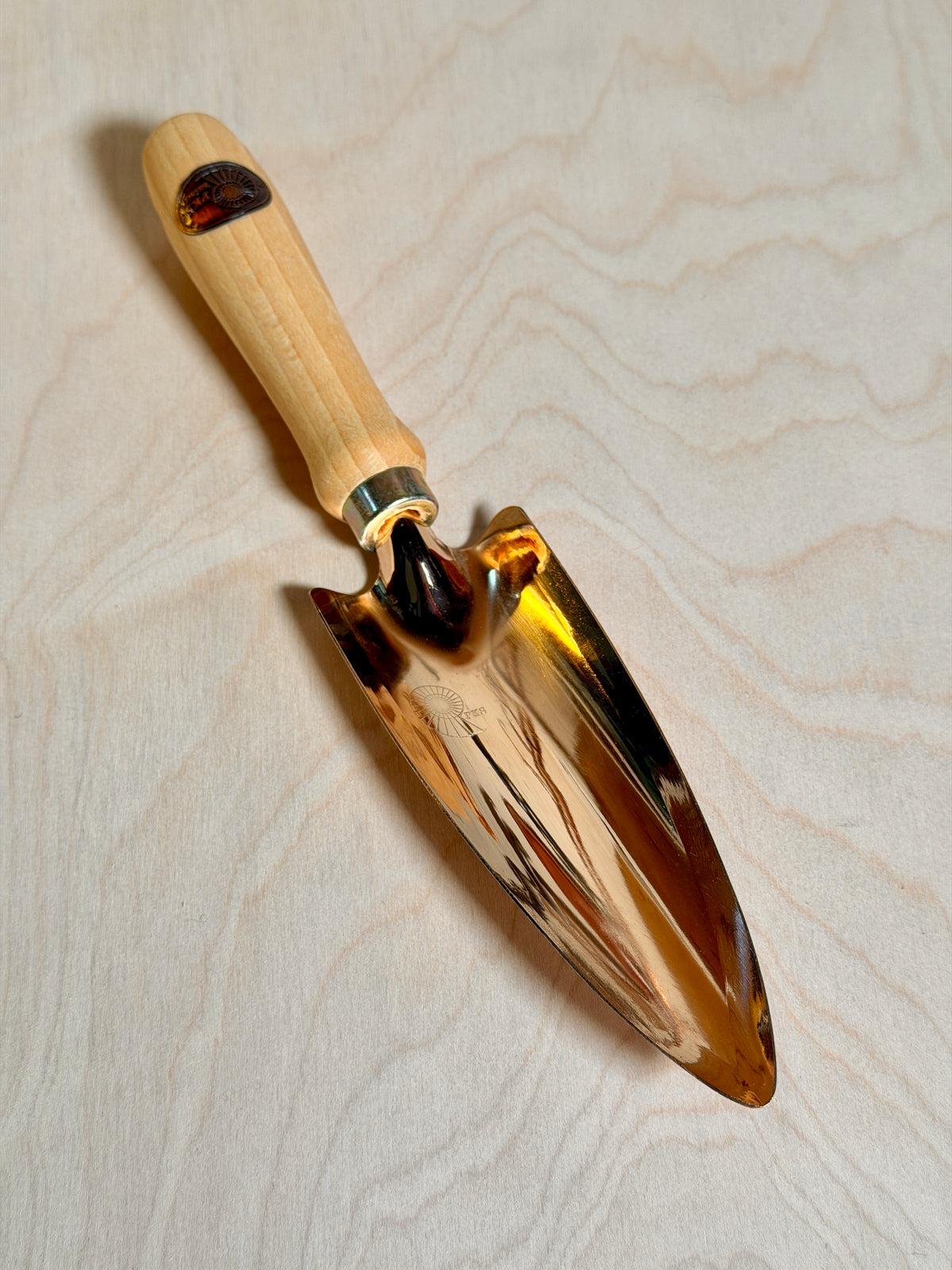 Bronze trowel on a birch ply background