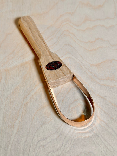 Bronze weeding tool on birch ply background