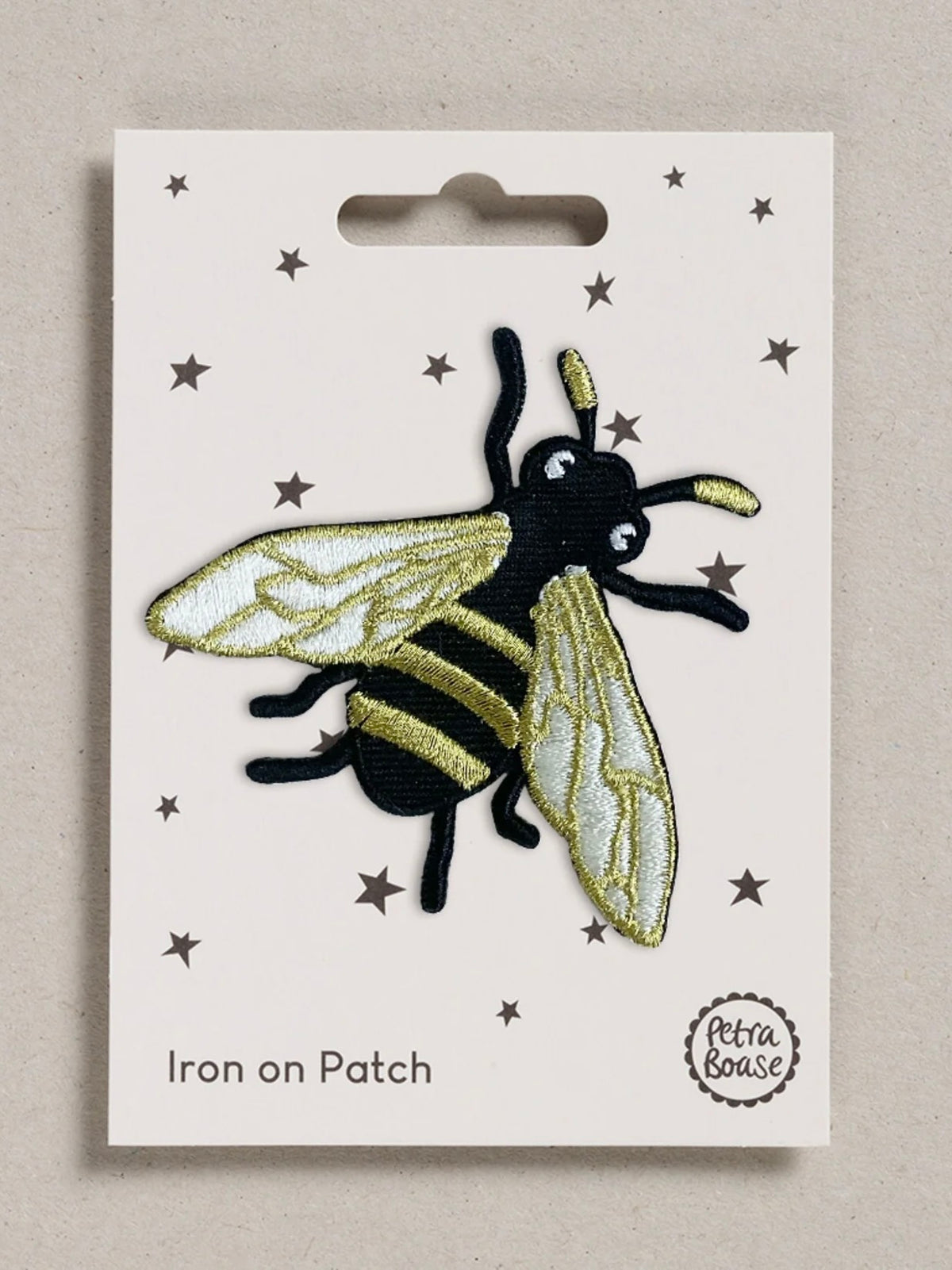 Bee-shaped iron on patch on a white card with star patterns