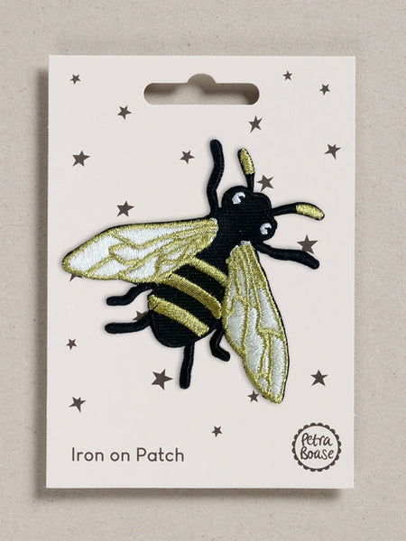 Bee-shaped iron on patch on a white card with star patterns