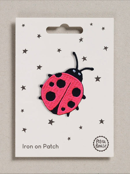Pink ladybird iron on patch on a white card with star patterns