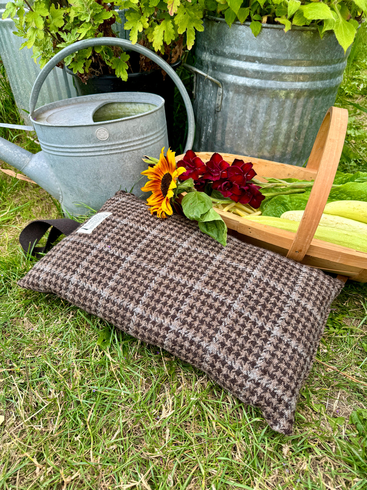 Wool garden kneeler cushion with herringbone pattern next to galvanised tub and watering can